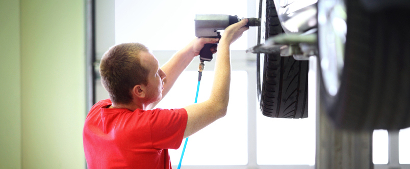 a mechanic working on the tires of a chevy car
