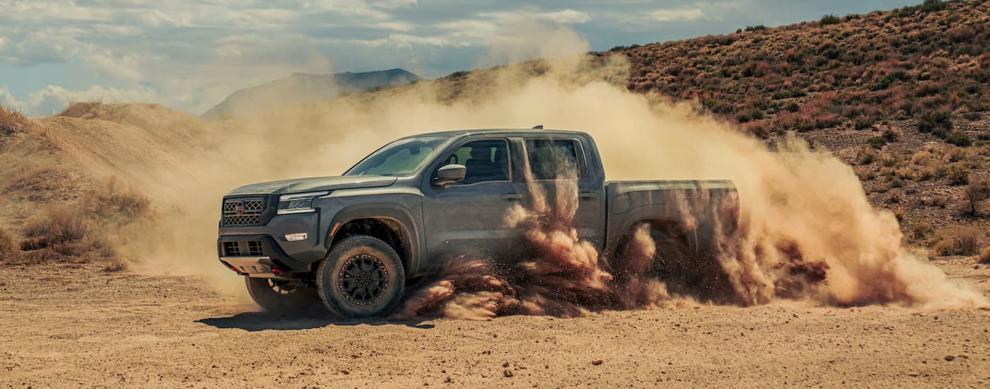 Dark grey 2022 Nissan Frontier doing donuts in dirt close to a Nissan dealer near you