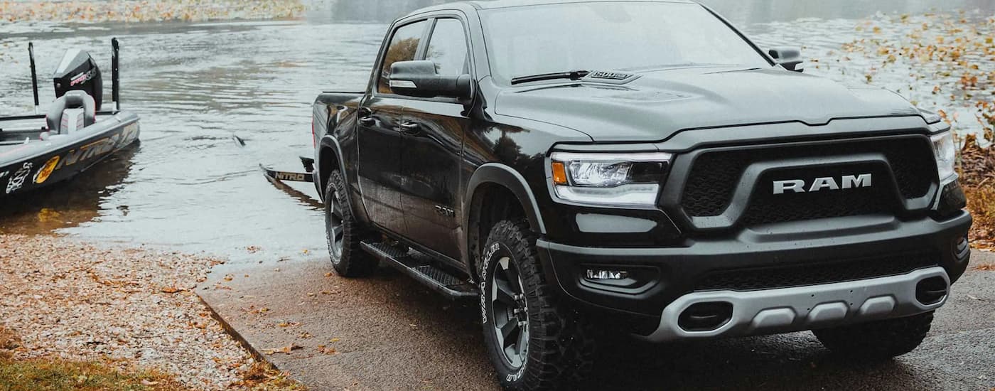 A black 2022 Ram 1500 is shown towing a boat out of a body of water.