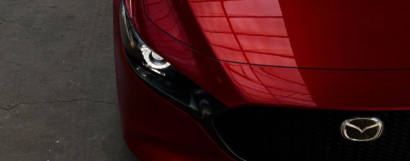 Close up of the passenger side headlight of a red 2019 Mazda3