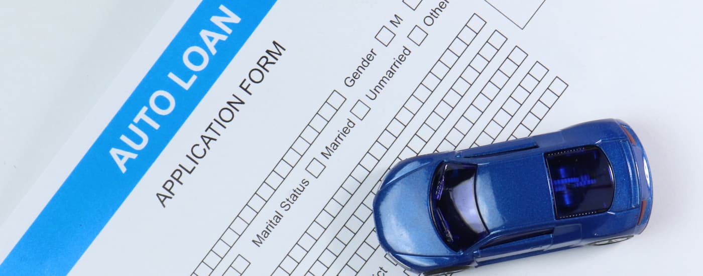 A blue toy car sitting on top of an auto loan application form