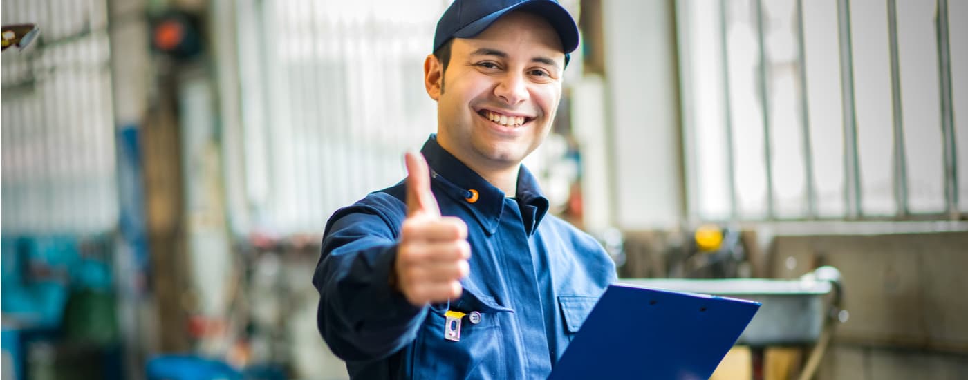 Nissan service technician holding a clipboard and giving a thumbs up
