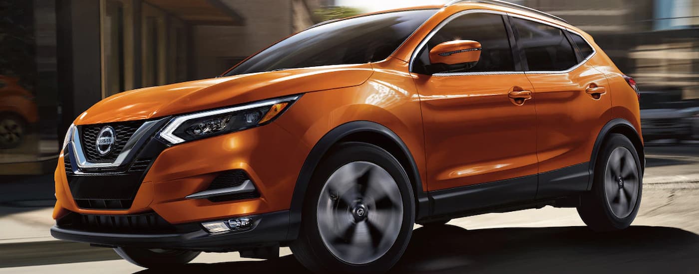 An orange 2022 Nissan Qashqai driving down the city street