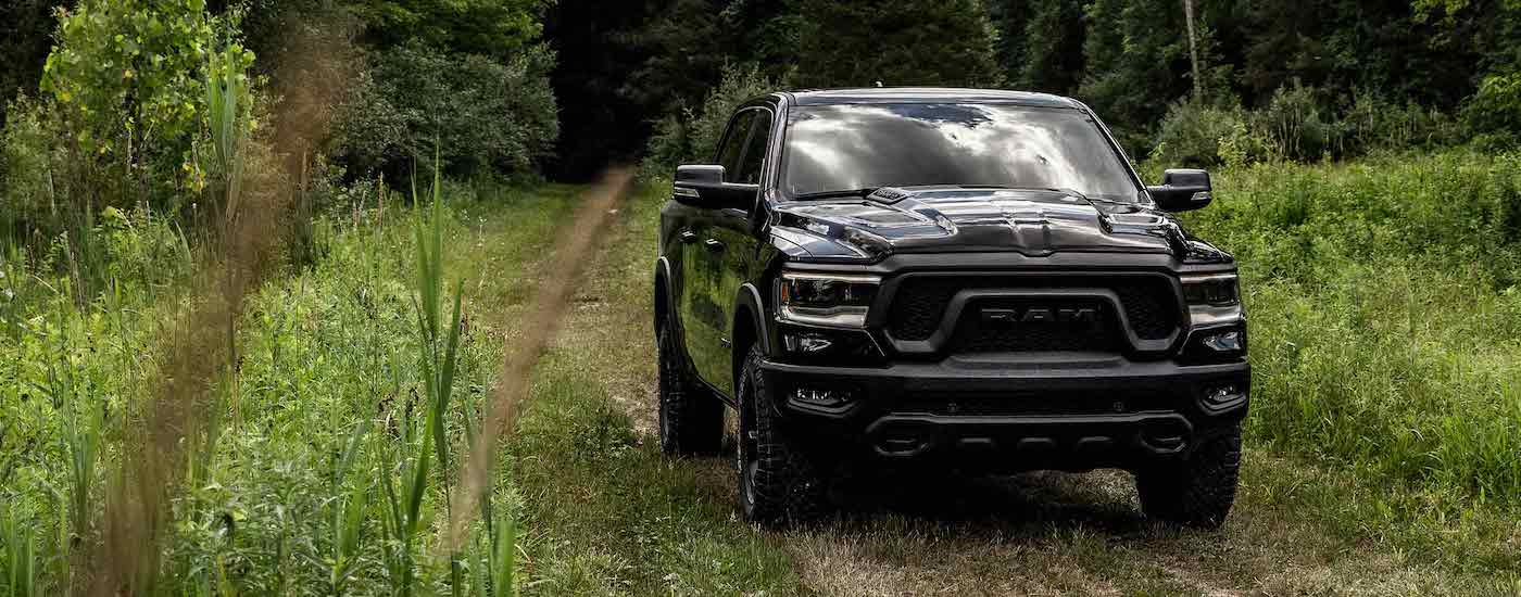 A black 2022 Ram 1500 Rebel is shown driving on a path after visiting a Ram dealer near you.