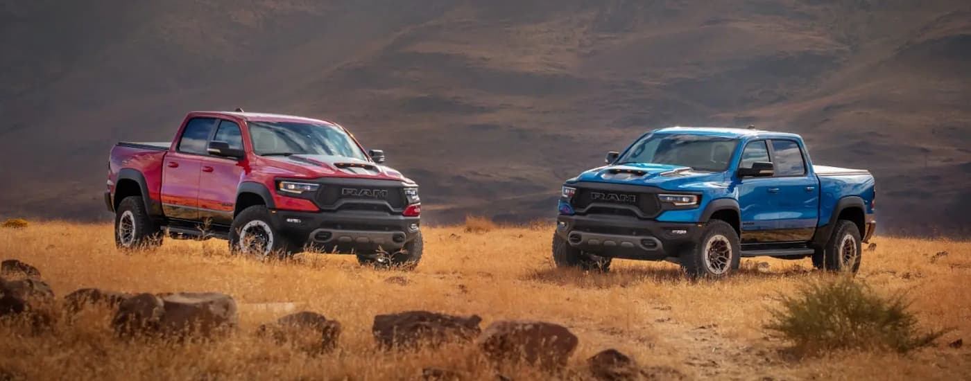 A red and a blue 2022 Ram 1500 TRX are shown facing each other parked on a field.