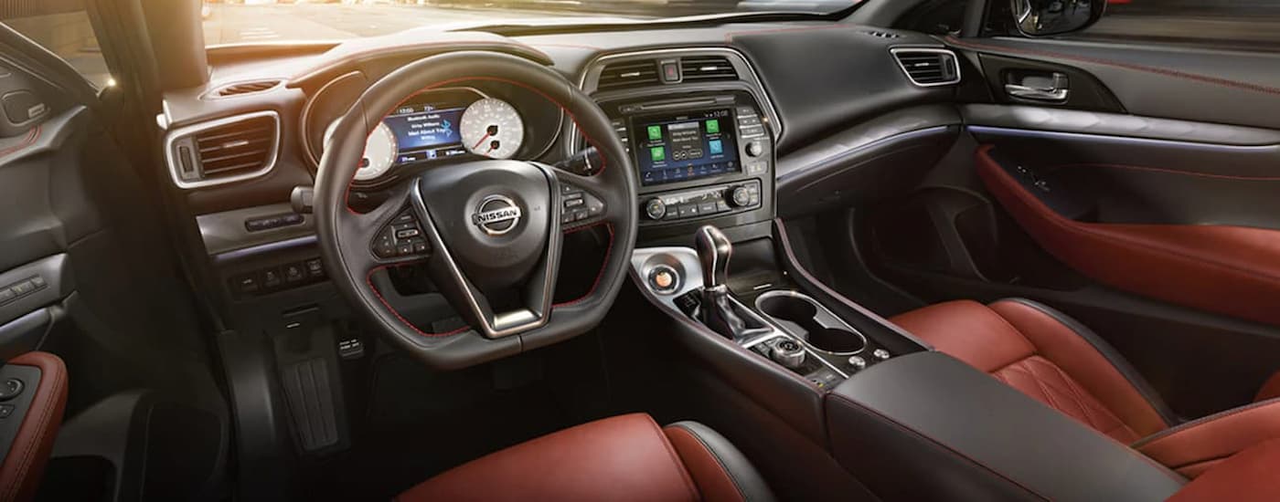 The black and red interior of a 2021 Nissan Maxima shows the steering wheel and center console.