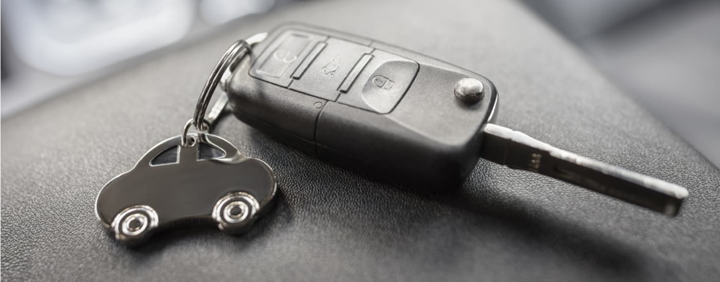 Car key with a vehicle keychain attached sitting on a black surface