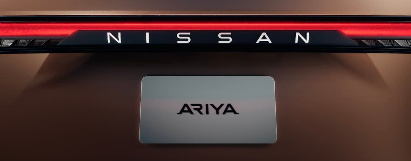 A close up of the rear badging and plate on a bronze 2022 Nissan Ariya