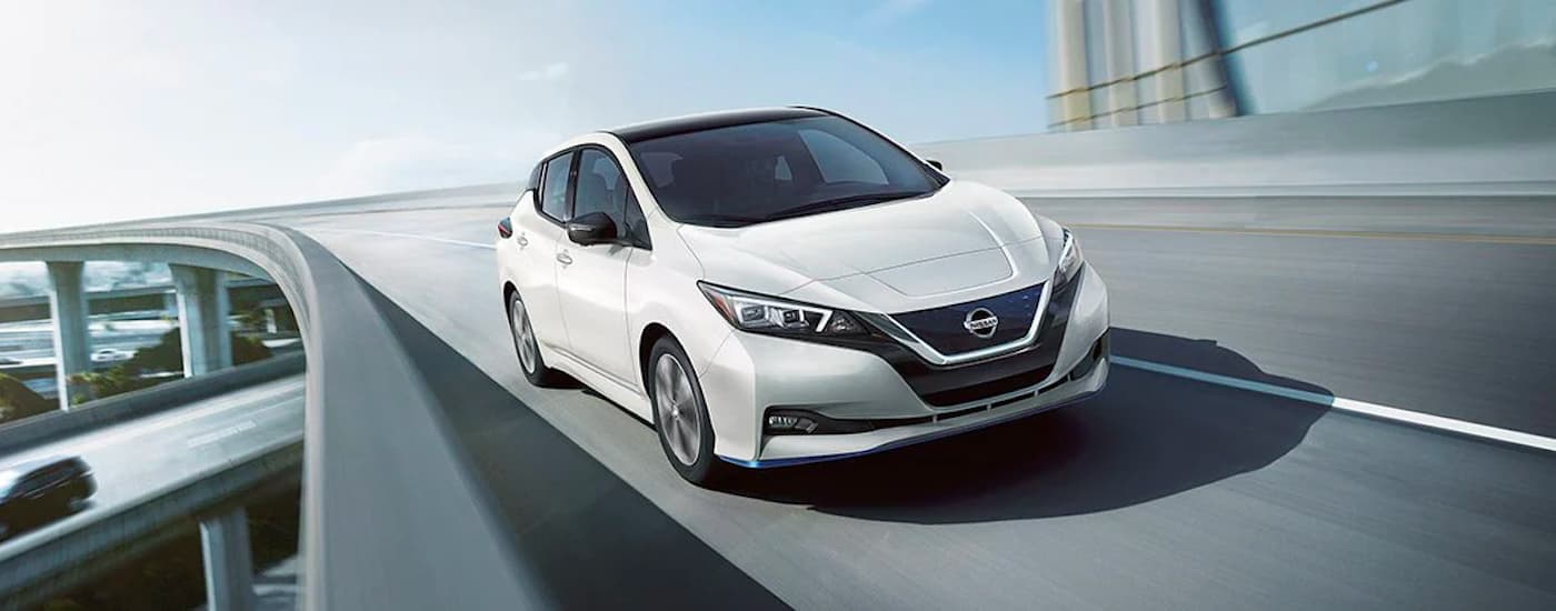 A white 2022 Nissan LEAF driving over a bridge