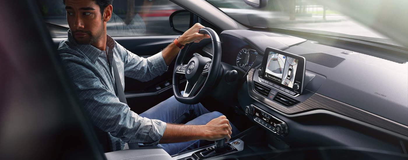 Man in a plaid shirt looking behind him as he backs up in a 2021 Nissan Altima