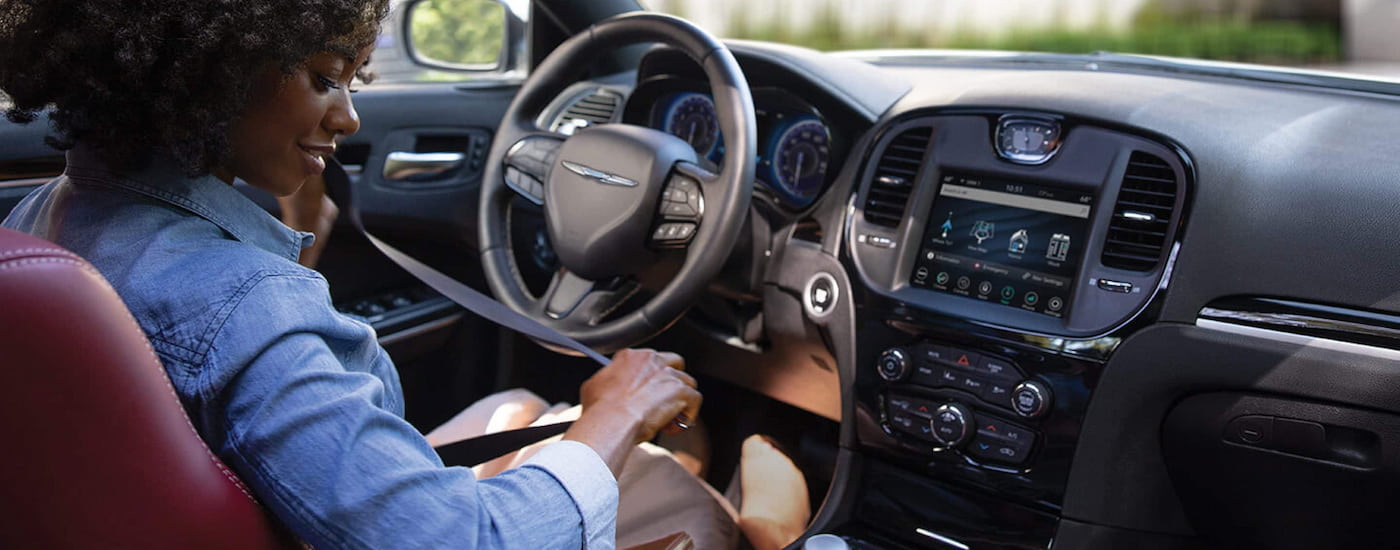 A woman is shown buckling into the driver's seat of a 2022 Chrysler 300.