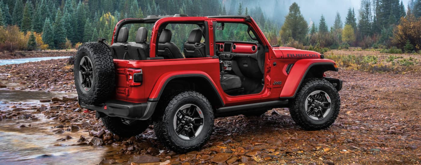A red 2020 Jeep Wrangler is shown parked near a river after leaving a used Jeep dealer.