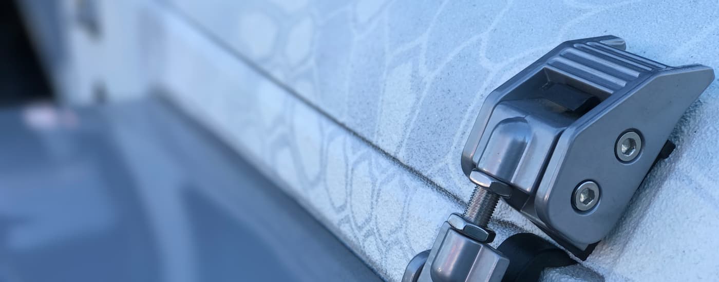 A close up of the hood latch is shown on a white Jeep.