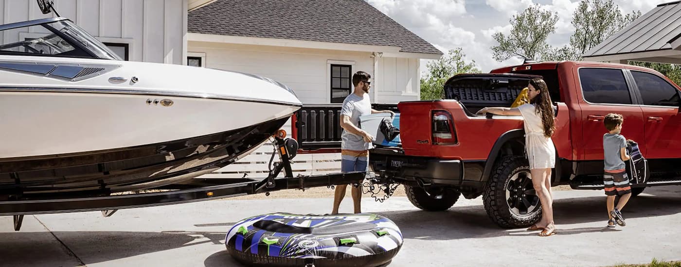 A family is shown standing around a red 2022 Ram 1500 towing a boat.