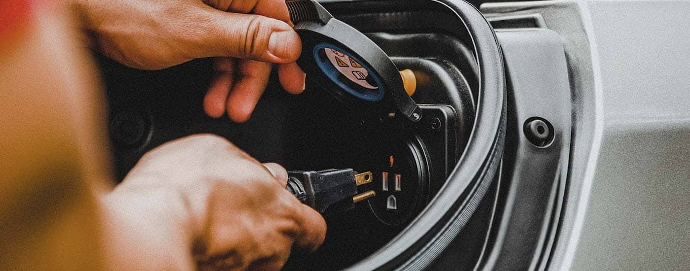 A person is shown plugging a cord into the outlet inside of a RamBox.