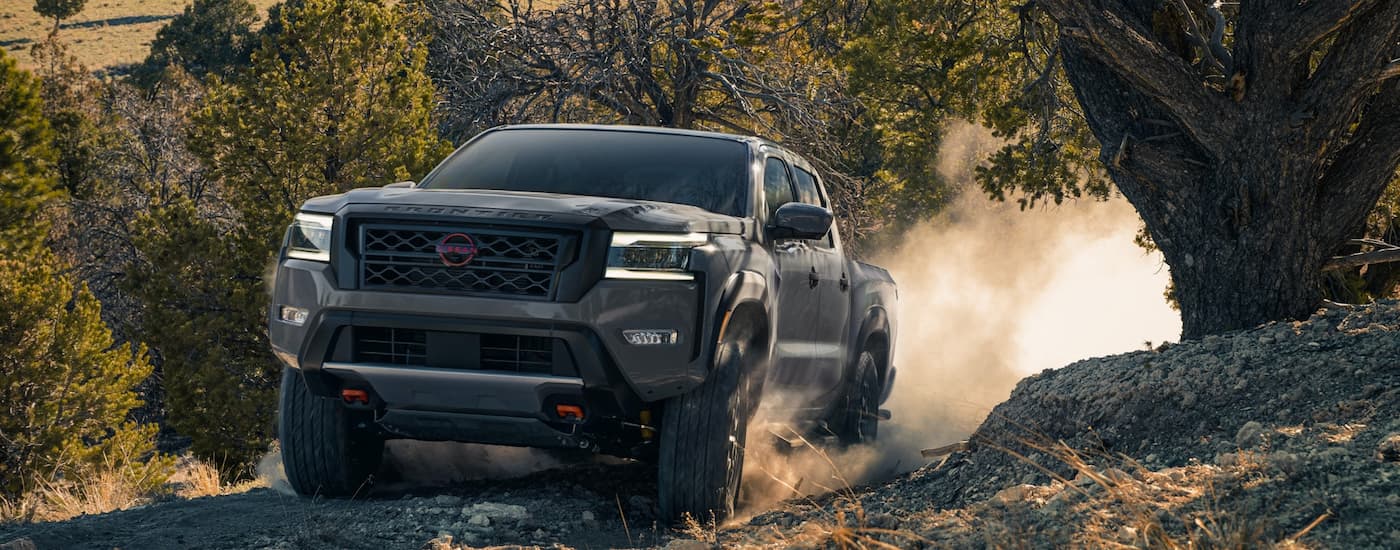 Front view of a grey 2022 Nissan Frontier Pro-4X driving up a steep off-roading path