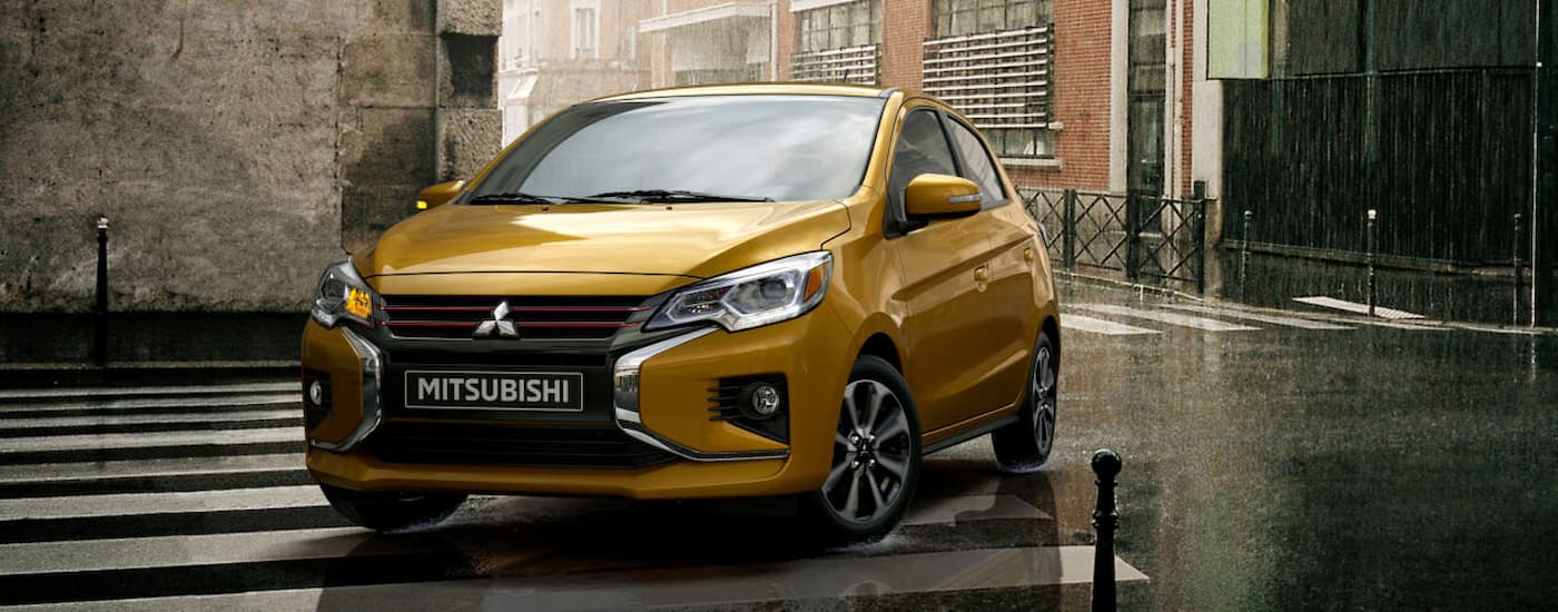 A yellow 2022 Mitsubishi Mirage is shown driving on a city street after visiting a used Mitsubishi dealership.