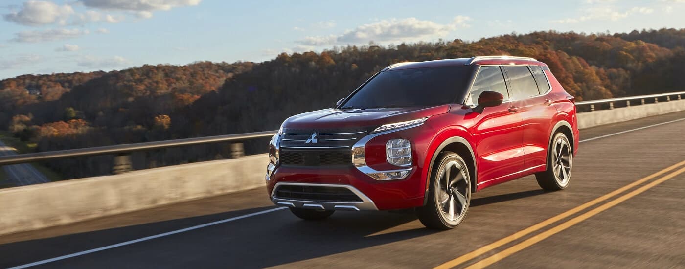 A red 2022 Mitsubishi Outlander is shown driving on an open road.