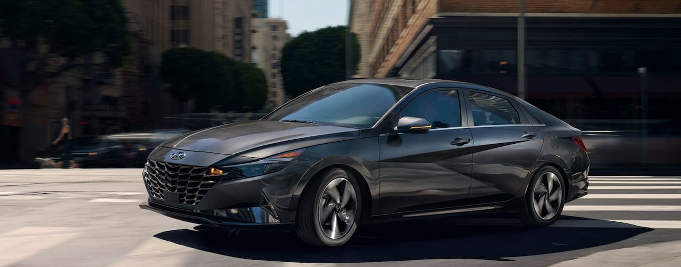A dark grey 2022 Hyundai Elantra driving through the city after leaving a Hyundai dealer near you