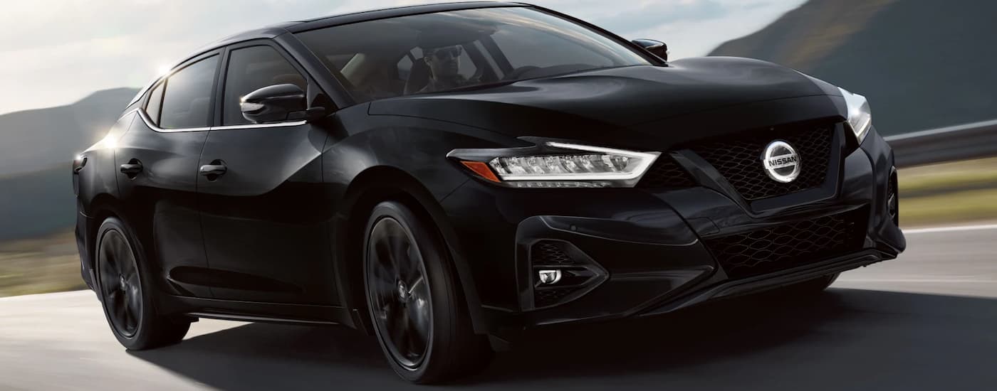 A black 2022 Nissan Maxima driving down the road after leaving a Nissan dealer
