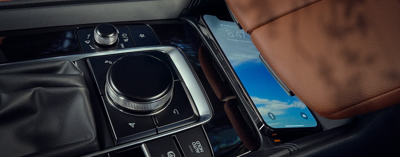 Close up of a cell phone sitting on the center console in a 2023 Mazda CX-50.