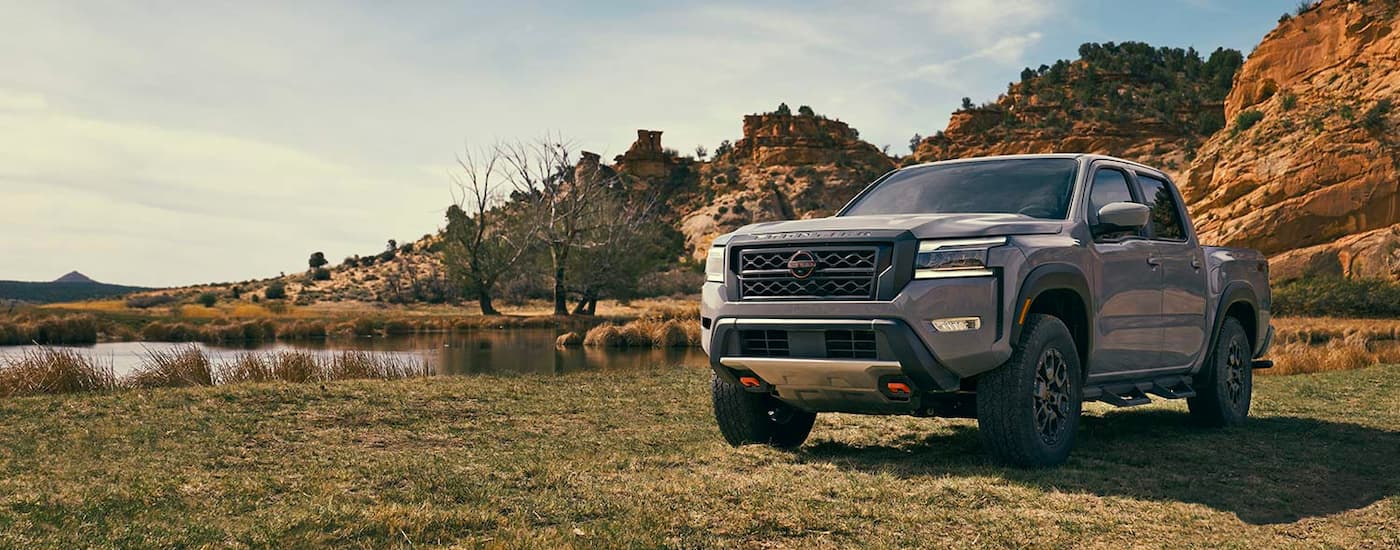 A dark grey 2022 Nissan Frontier Pro4x parked by a lake after leaving a Nissan dealer