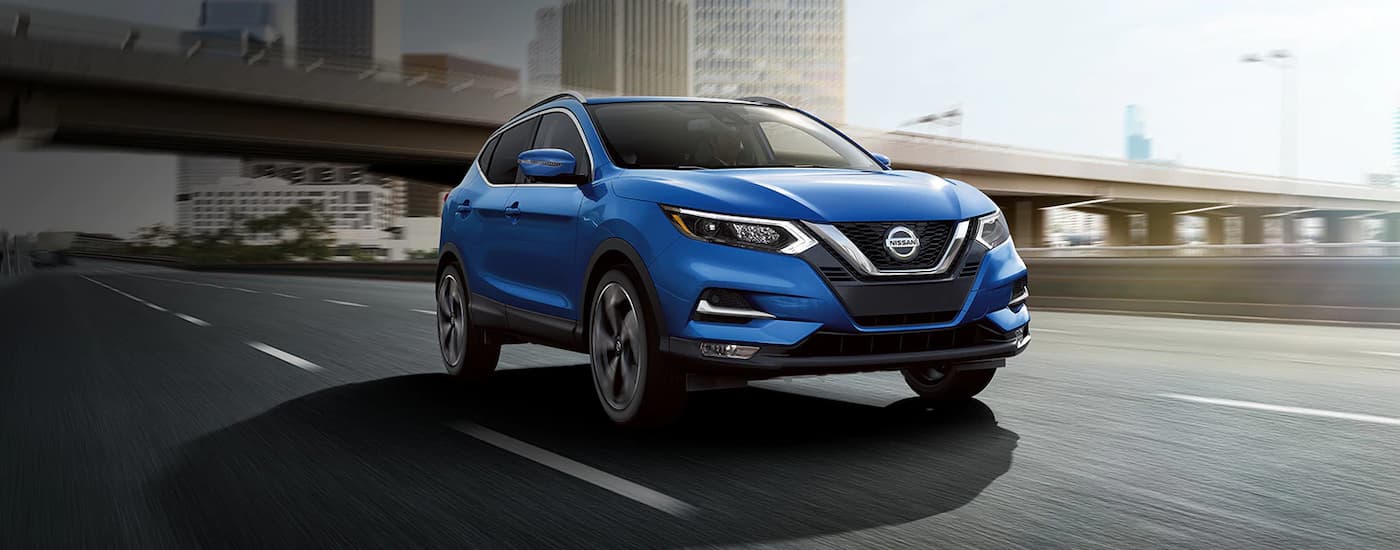 Front view of a blue 2022 Nissan Rogue Sport driving down an empty highway