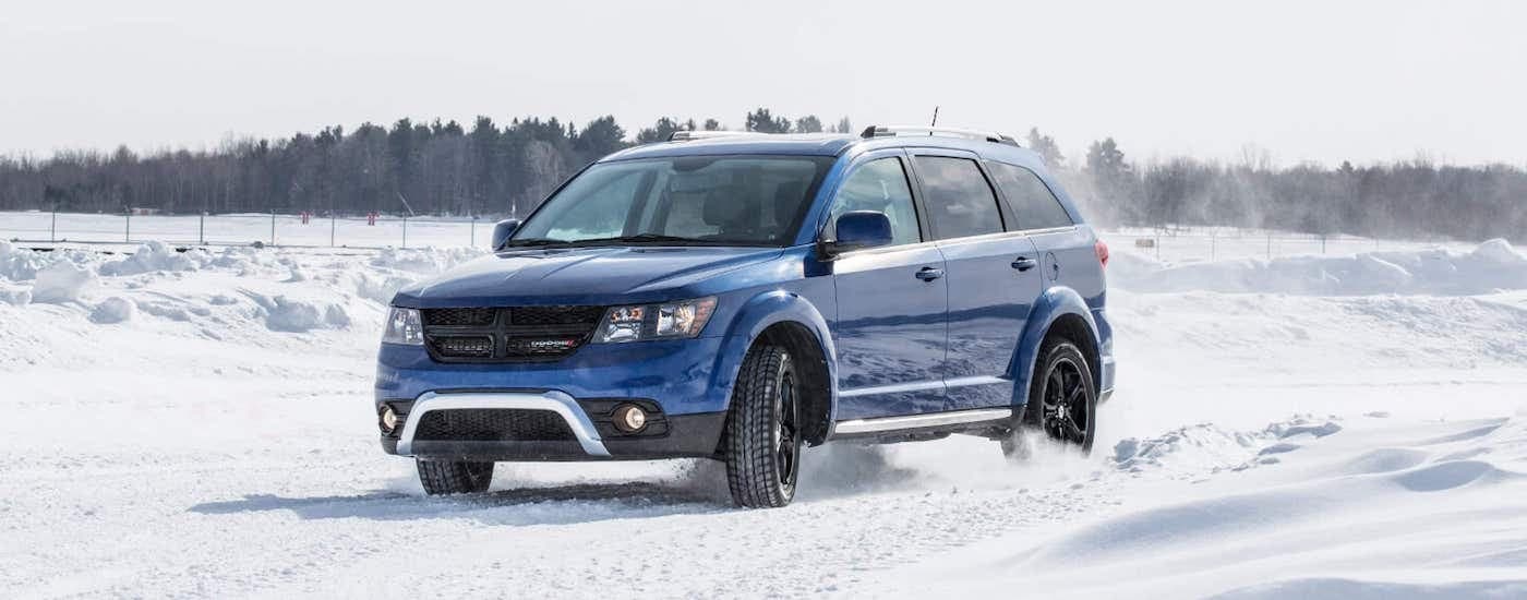 A blue 2020 Dodge Journey is shown driving on a snowy path after leaving a used Dodge dealer.