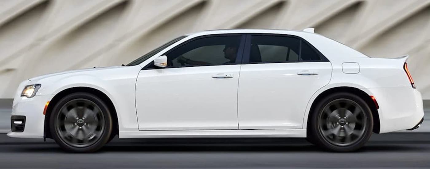 A white 2019 Chrysler 300 is shown from the side parked in front of a wall.