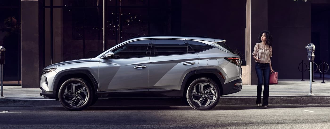Side view of a silver Hyundai Tucson parked outside a city building 