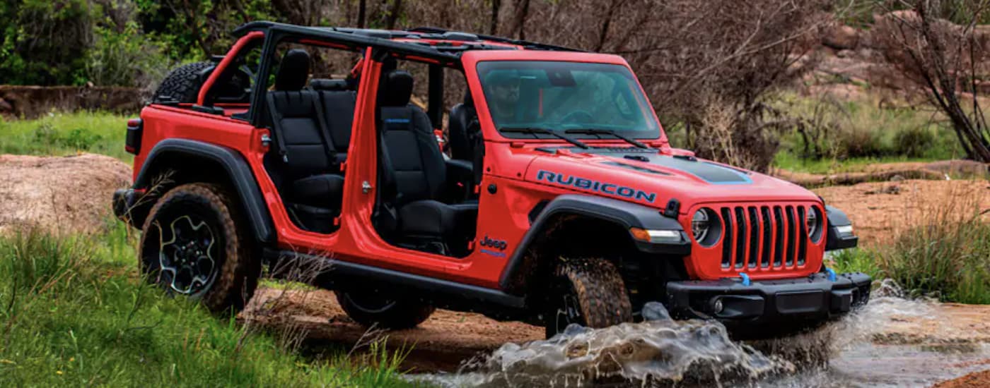 A red 2022 Jeep Wrangler 4xe is shown from the side off-roading after leaving a Jeep Wrangler dealer. 