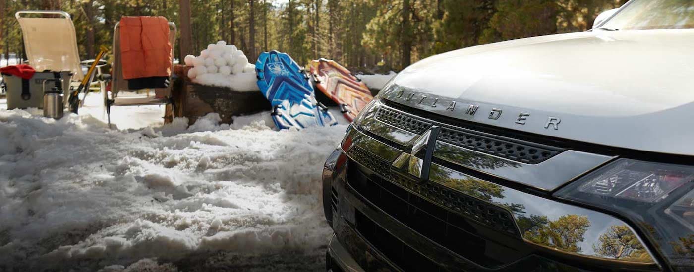 A grey 2021 Mitsubishi Outlander PHEV is shown parked next to snow and sleds.