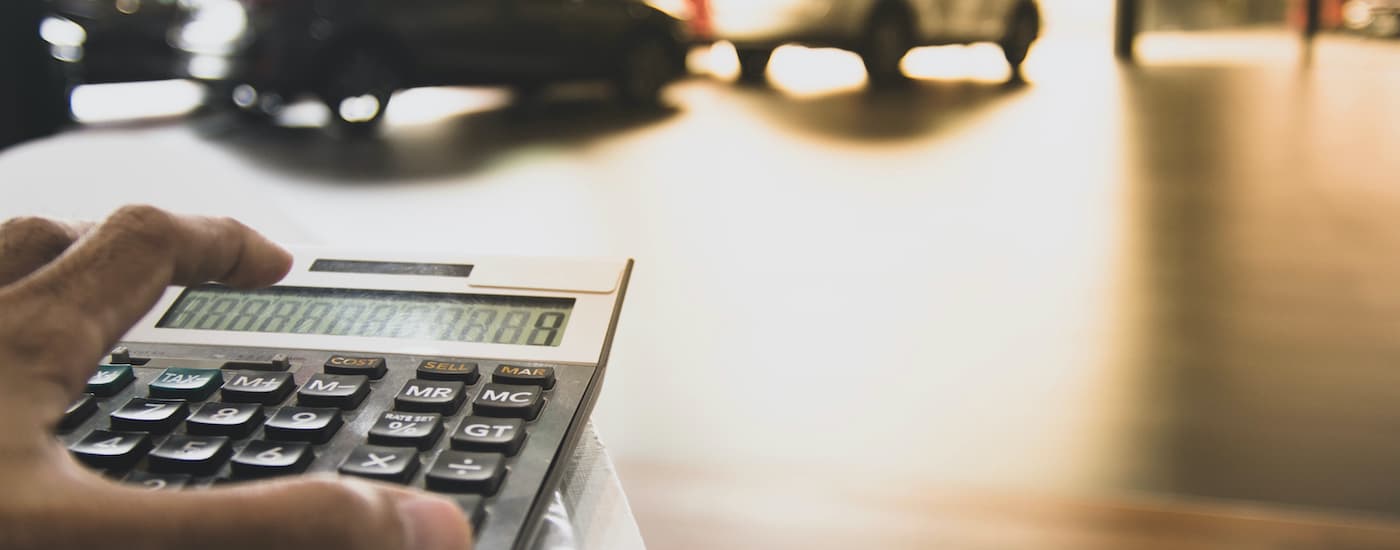 A person is shown using a calculator for used car financing.