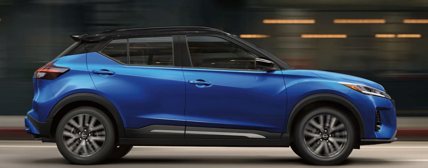 A blue 2022 Nissan Kicks is shown from the side driving on an open road after leaving a Nissan dealer near Beaumont. 