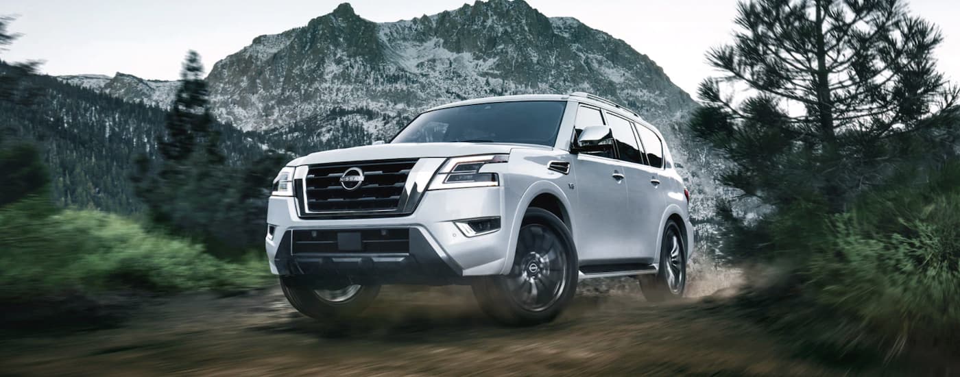 A white 2022 Nissan Armada is shown from the front driving on a dirt road.