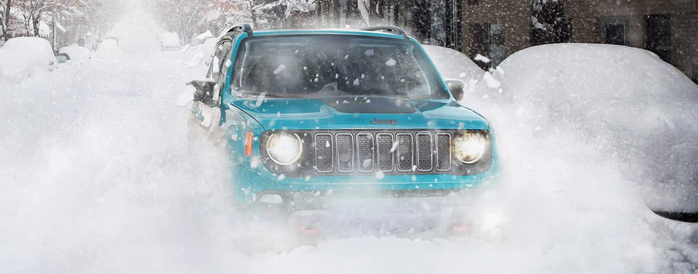 A teal 2022 Jeep Renegade Trailhawk is shown from the front kicking up snow.