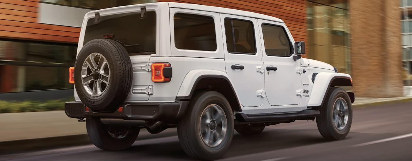 A white 2022 Jeep Wrangler is shown from the side driving on an open road.