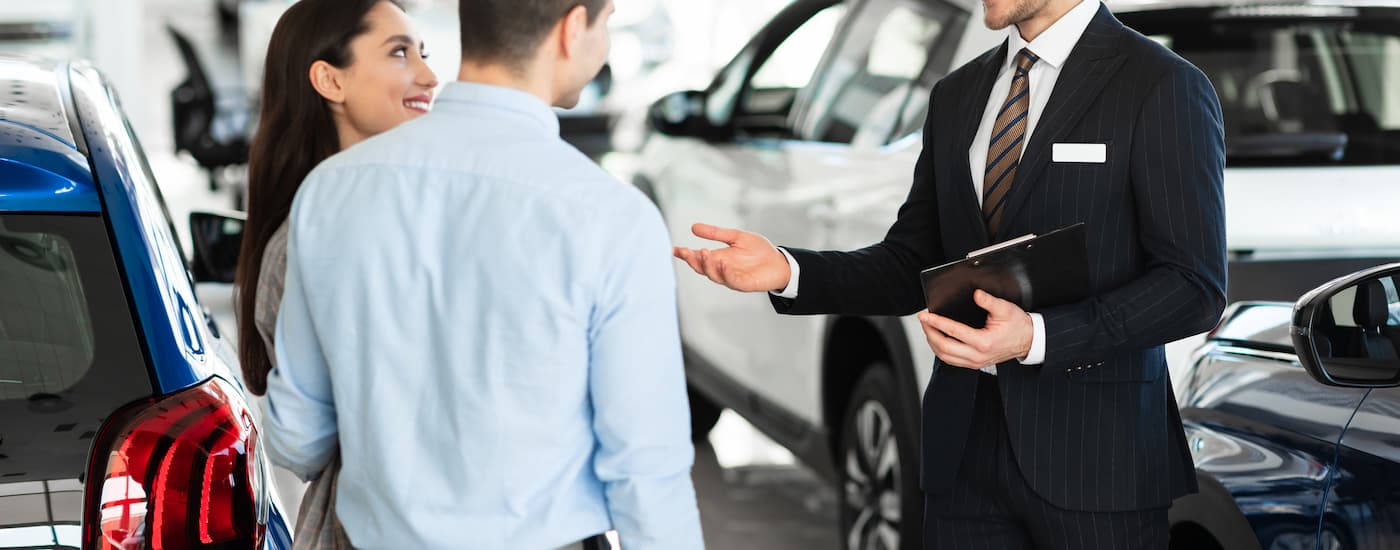 A car salesman is shown speaking to customers about car loans in Fort McMurray.