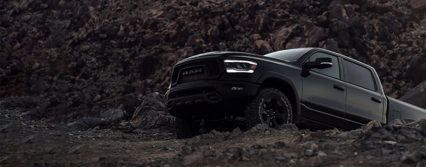 A black 2022 Ram 1500 is shown driving on a rocky trail.