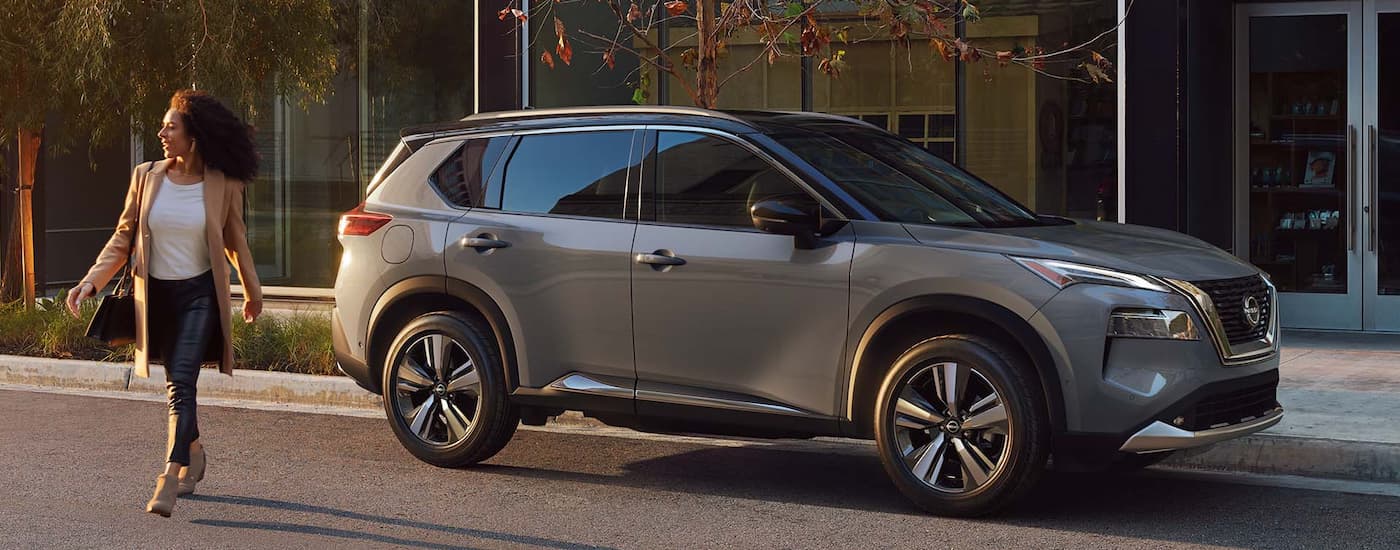 A woman is shown walking past a grey 2022 Nissan Rogue.