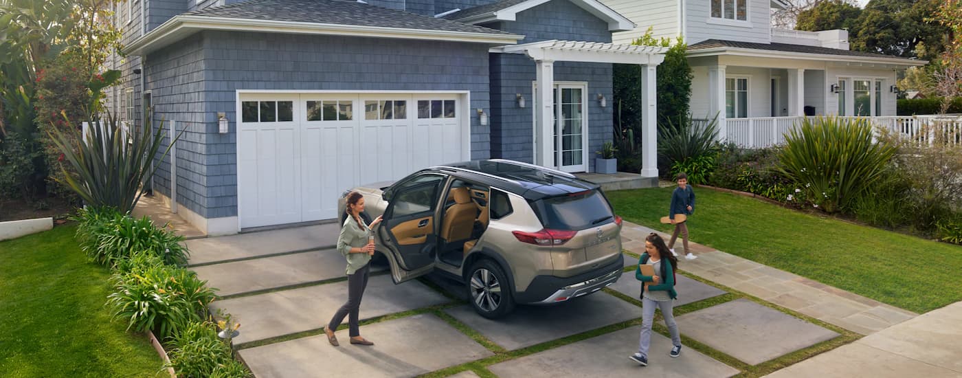 A tan 2022 Nissan Rogue is shown in a driveway.