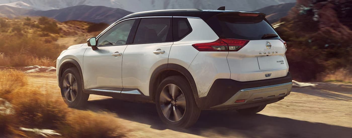 A white 2022 Nissan Rogue Platinum is shown driving on a dirt trail.