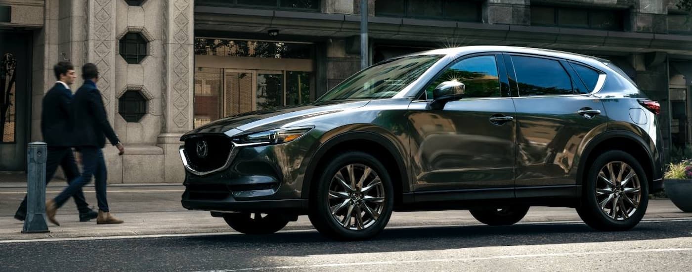 A grey 2022 CX-5 is shown parked on the side of a city street.