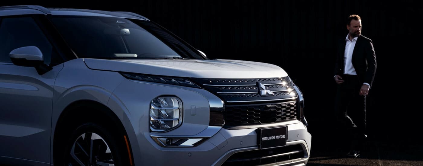 A man is shown walking by a silver 2022 Mitsubishi Outlander. 