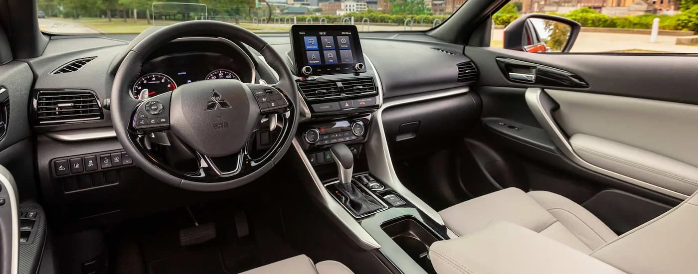 The black and tan interior of a 2023 Mitsubishi Eclipse Cross shows the steering wheel and center console.