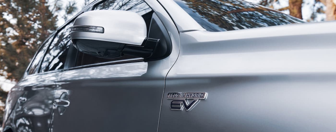 The side of a Mitsubishi SUV, a silver 2022 Mitsubishi Outlander PHEV is shown.