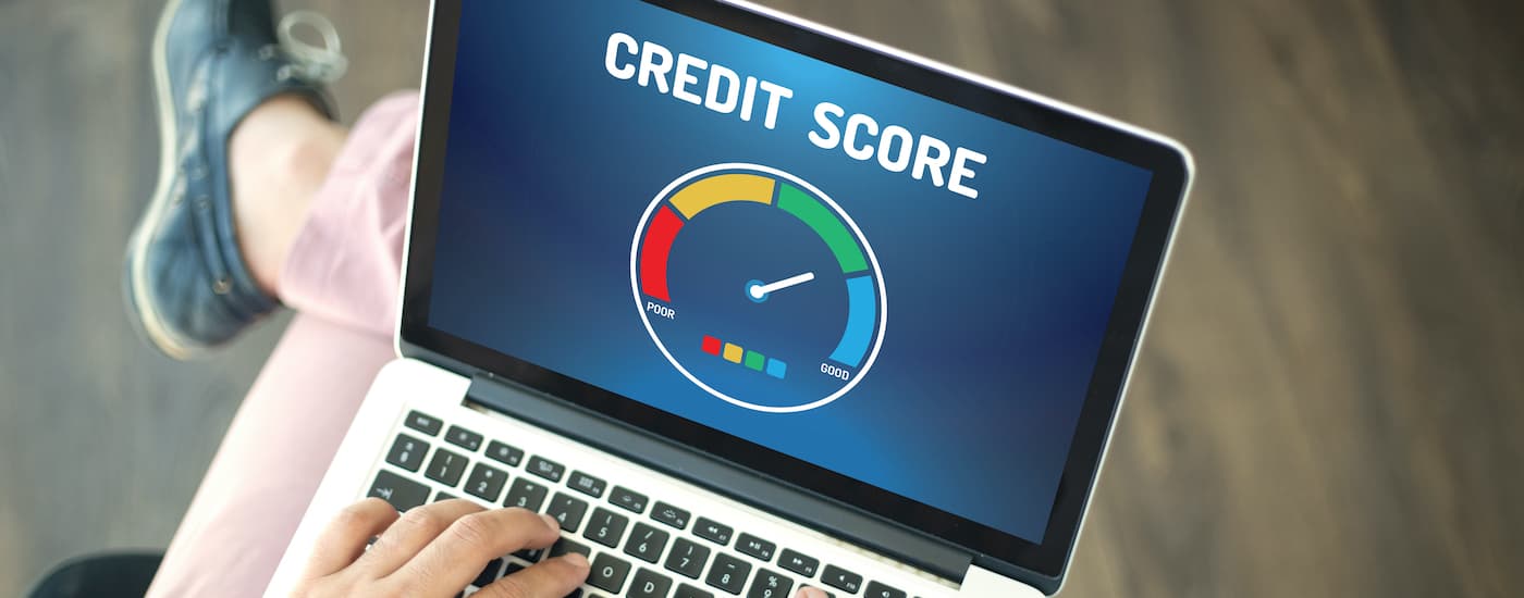 A person is shown looking at their credit score on a computer.