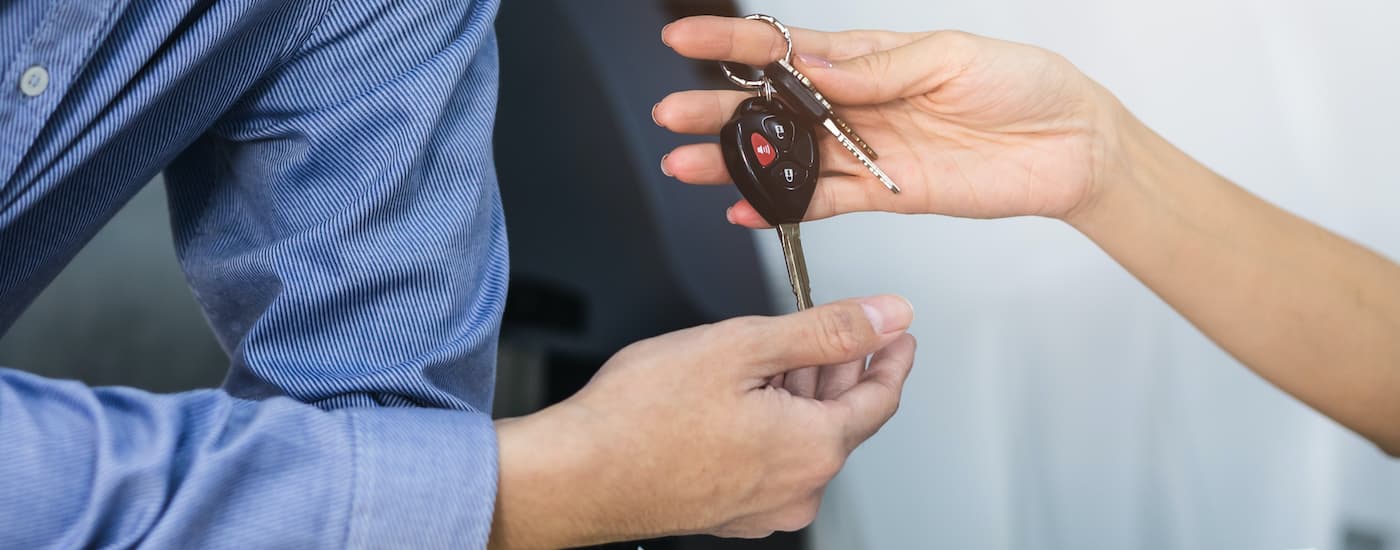A person is shown passing a car key after getting help with bad credit car loans in Leduc.