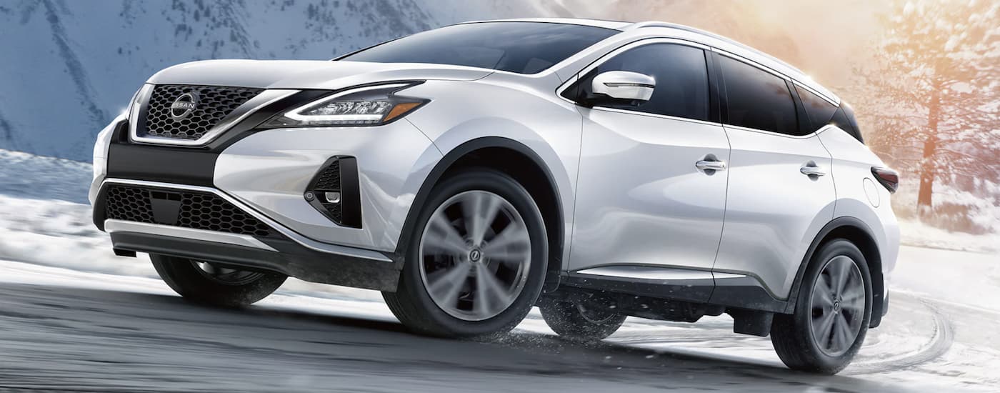 A white 2022 Nissan Murano is shown driving on a snowy road.
