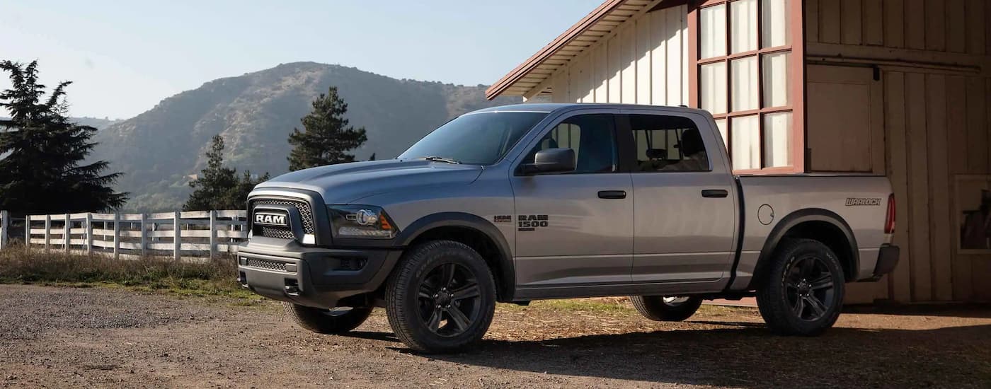 A silver 2022 Ram 1500 Classic Warlock is shown parked outside of a farm.